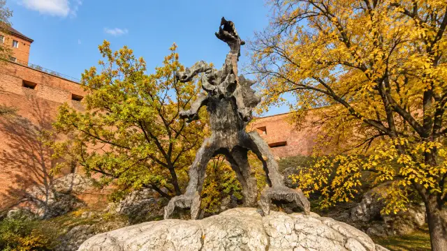 The bronze Wawel Dragon statue at the foot of the castle hill, beside the River Vistula in Kraków