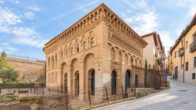 Brick façade of the Cristo de la Luz mosque in Toledo, with arches and a band of brick lettering along the top