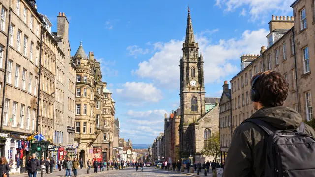 Una persona con auriculares descubre una calle de Edimburgo.